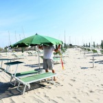 Foto Nicoloro G.   23-05-2020   Cervia (Ravenna)   La regione Emilia-Romagna ha anticipato di due giorni l\' apertura della stagione balneare. Tuttavia pochissimi sono gli stabilimenti pronti a cominciare, mentre la maggior parte e\' ancora indietro con i preparativi, come dimostrano chilometri di litorale vuoti in corrispondenza degli stabilimenti balneari. nella foto il titolare del Bagno Sorriso apre alle 8 di mattina quello che, molto probabilmente, e\' il primo ombrellone della stagione, per una famiglia di Bologna.