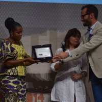 Foto Nicoloro G. 06/09/2014  Riccione ( Rimini )  Serata conclusiva con premiazioni della ventesima edizione del \" Premio giornalistico televisivo Ilaria Alpi \" a venti anni dall\' uccisione della giornalista di Rai 3 e del suo cameraman avvenuta a Mogadiscio il 20 marzo 1994. nella foto la giornalista del Congo Solange Lusiku Nsimire, vincitrice del premio speciale Unicredit per il valore e il coraggio dimostrato nel suo paese, premiata da Manrico Lucchi di Unicredit.